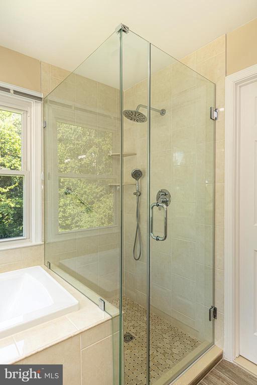 Bathroom with a glass-enclosed tiled shower, rainfall showerhead, and adjacent bathtub.