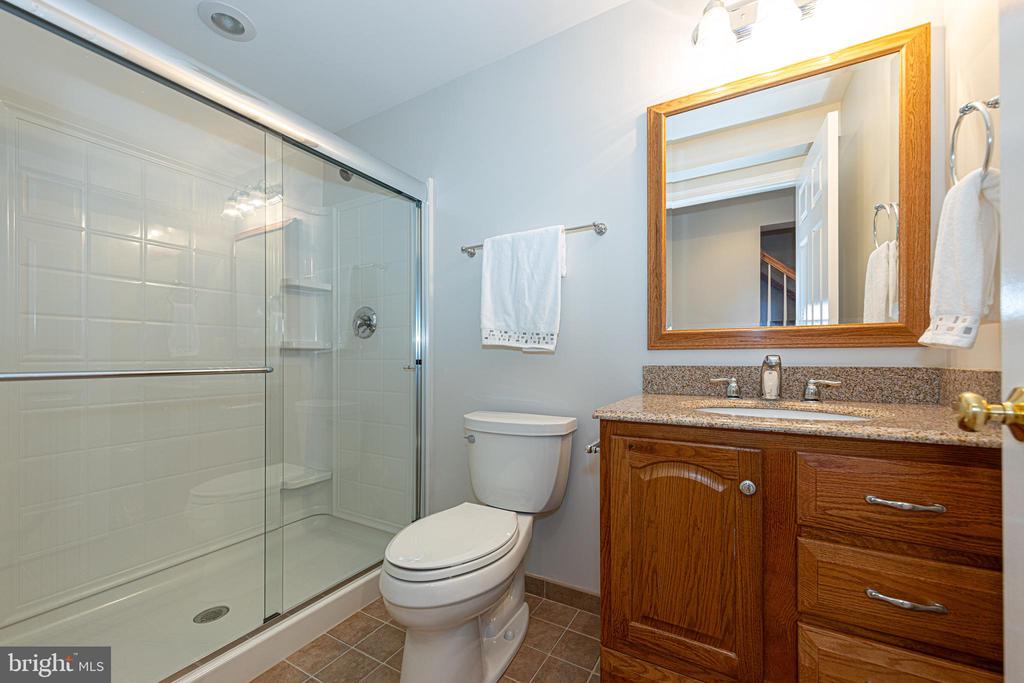 Bathroom with a glass shower enclosure and wood vanity topped with granite.