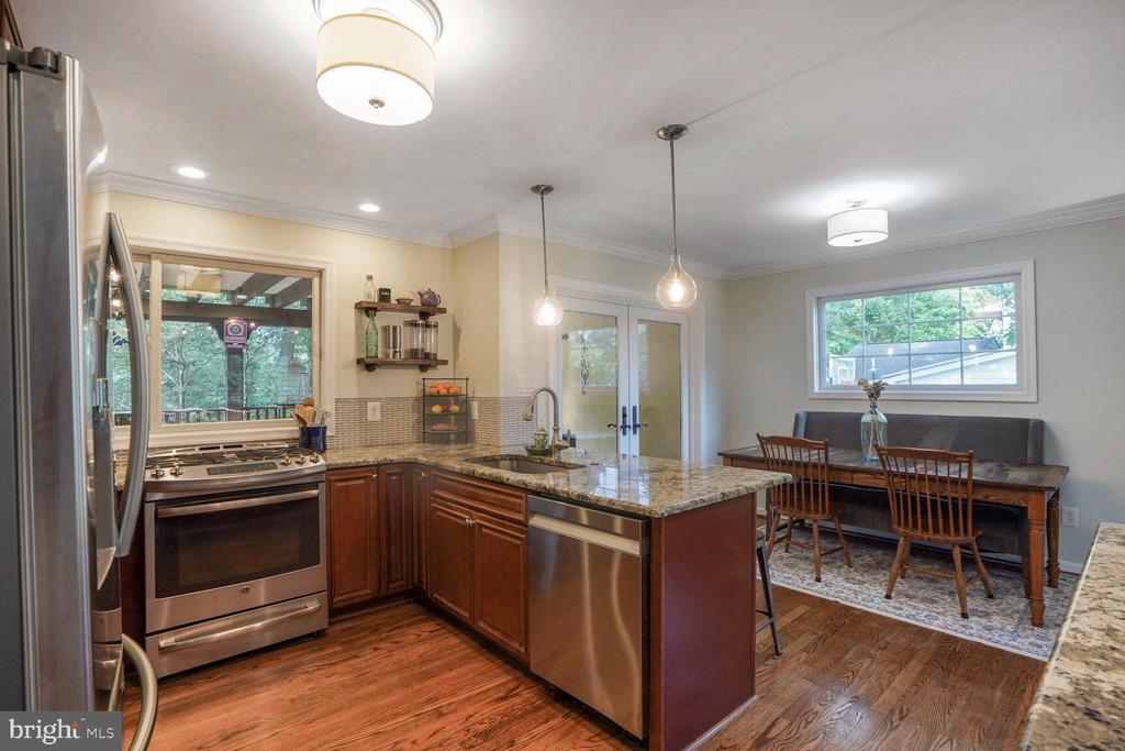 Kitchen and dining area with granite island, stainless steel appliances, and a wooden dining table.