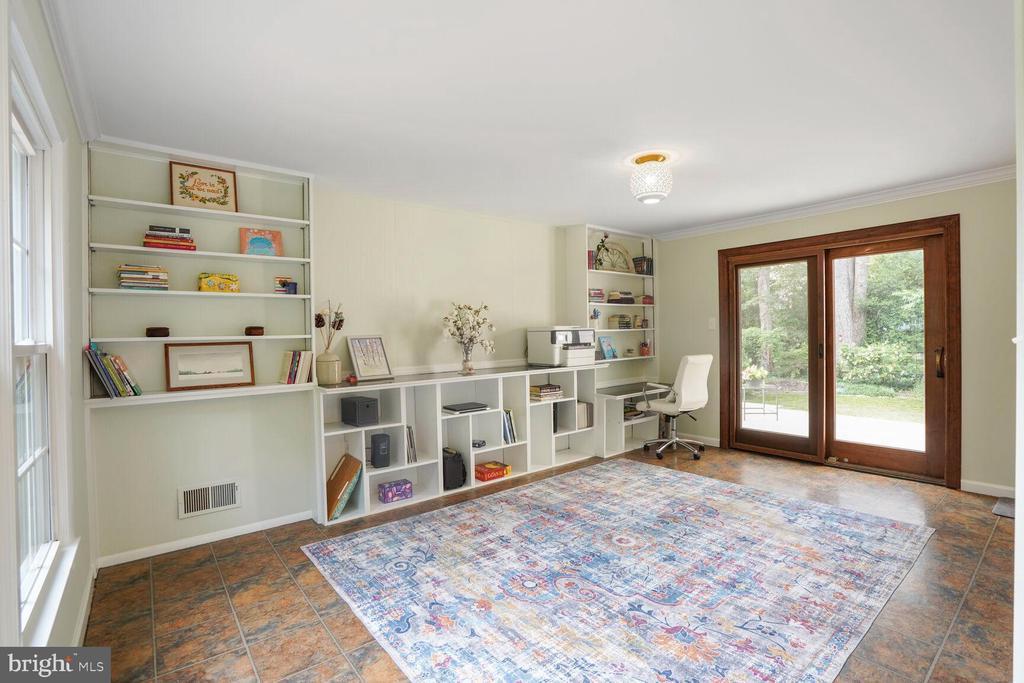 Home office with white built-ins, a patterned rug, and sliding glass doors to the yard.