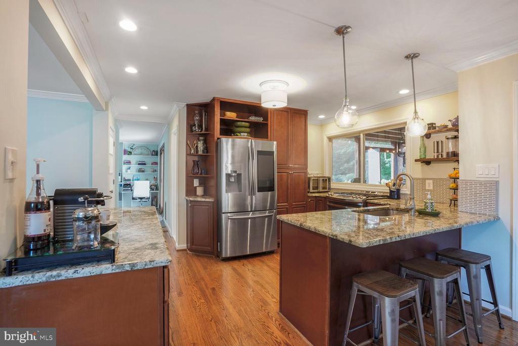 Kitchen with dark wood cabinets, stainless appliances, granite island, and hardwood floors.