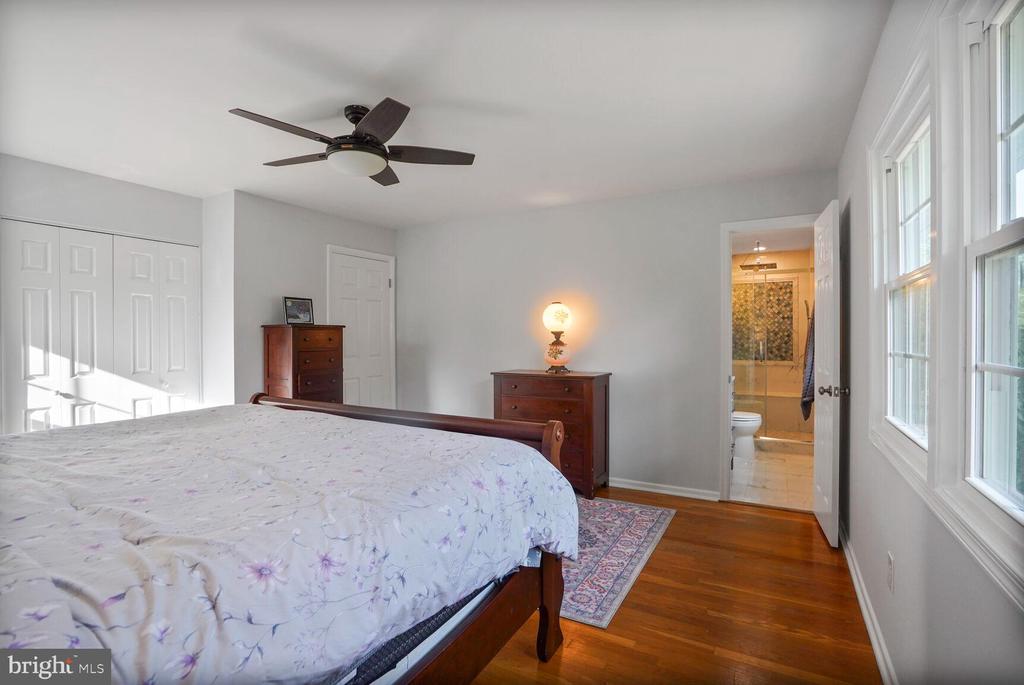 Bedroom with a dark wood bed, floral bedding, hardwood floors, and an adjoining bathroom.