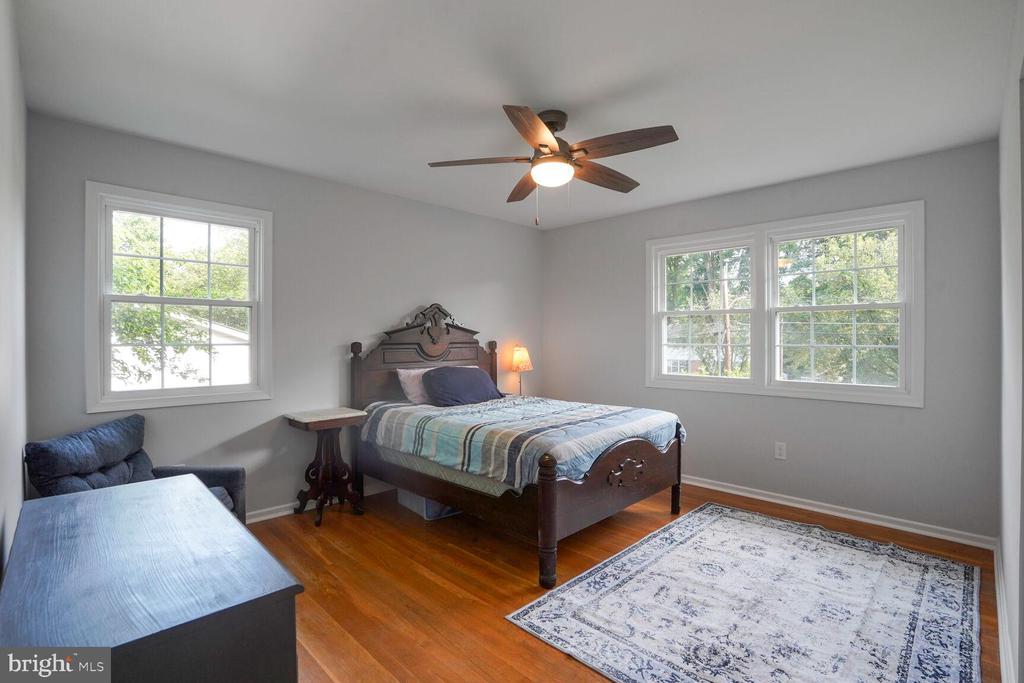 Bedroom with a carved dark wood bed, hardwood floors, and three windows.