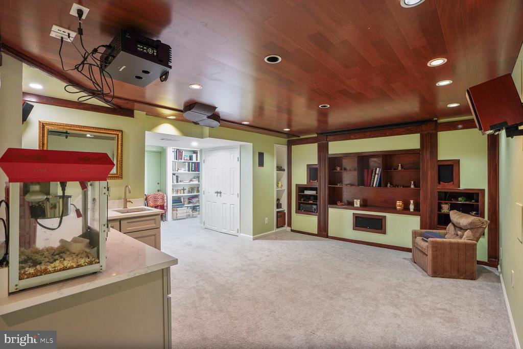 Finished basement recreation room with built-in media shelving, ceiling projector, and popcorn machine.