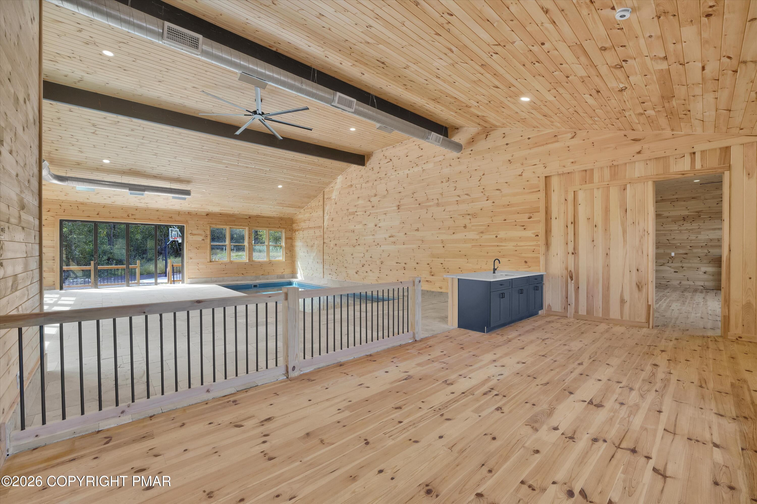 Indoor pool room with knotty pine finishes, exposed ducts, and a dark blue sink cabinet.