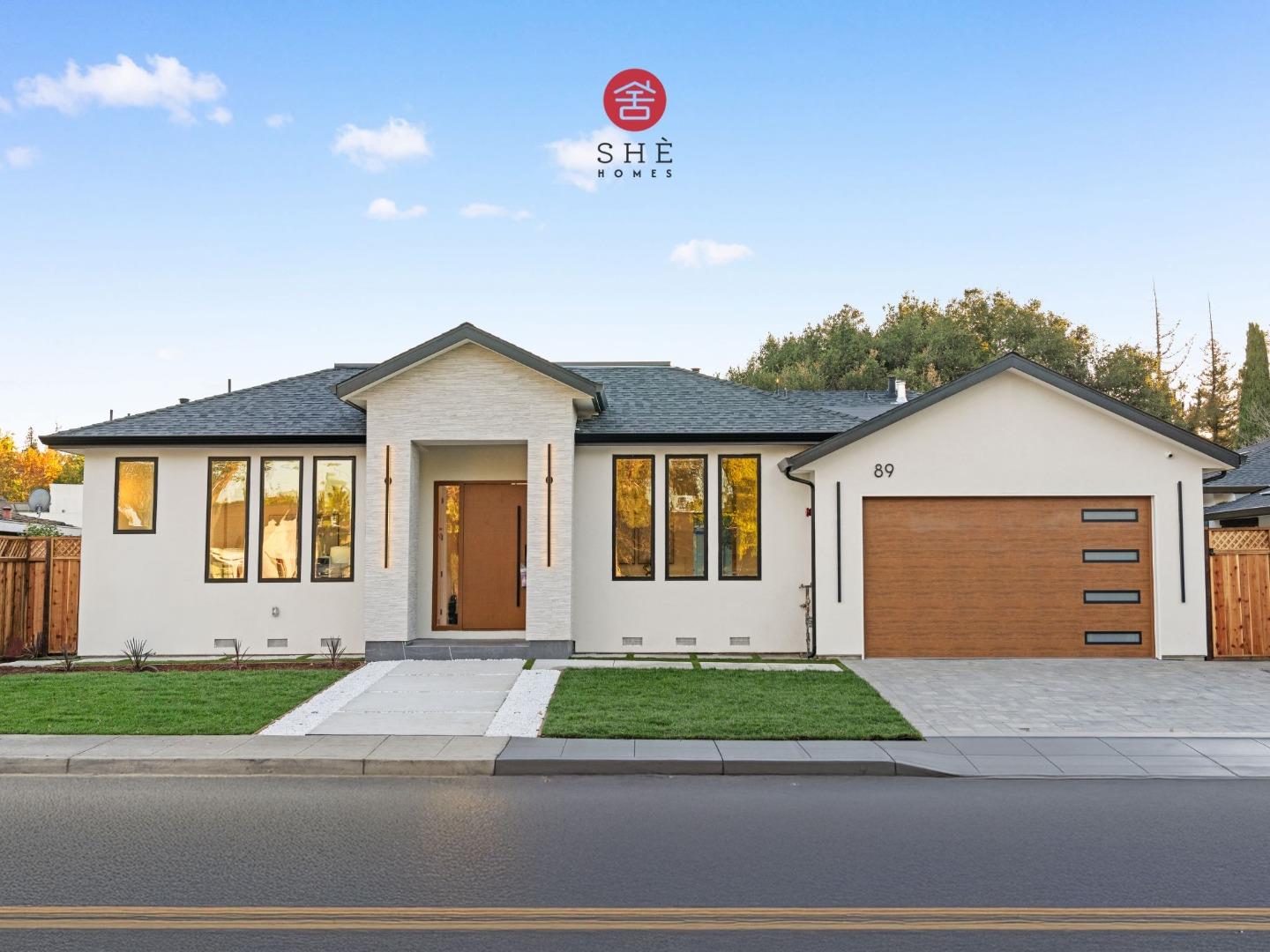 Modern white single-story home with a central entry, wood garage door, and front lawn.