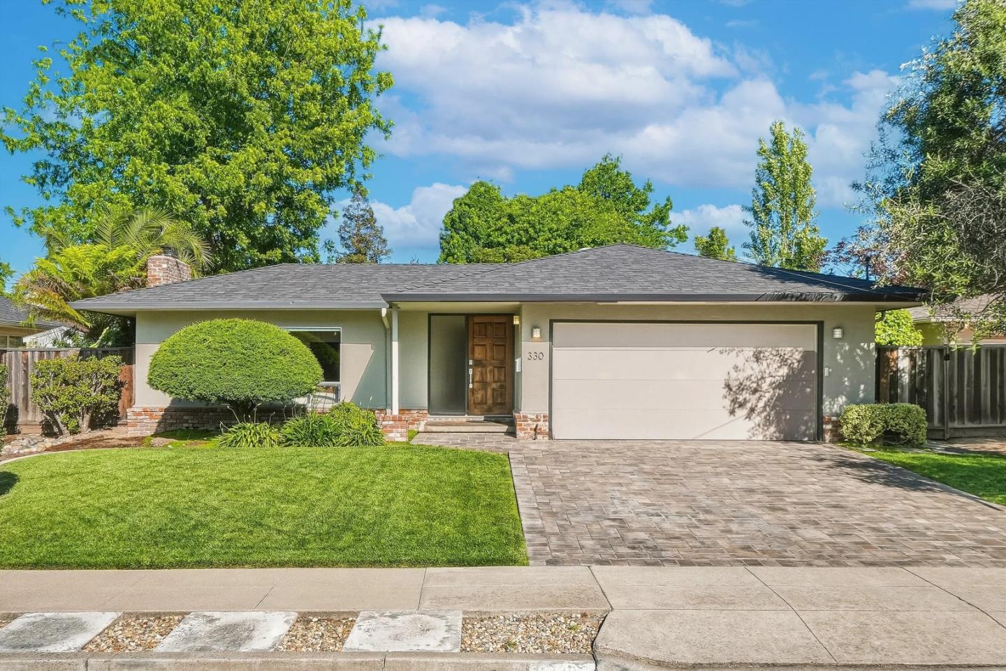 Single-story home with a wide garage, landscaped lawn, and paved driveway.