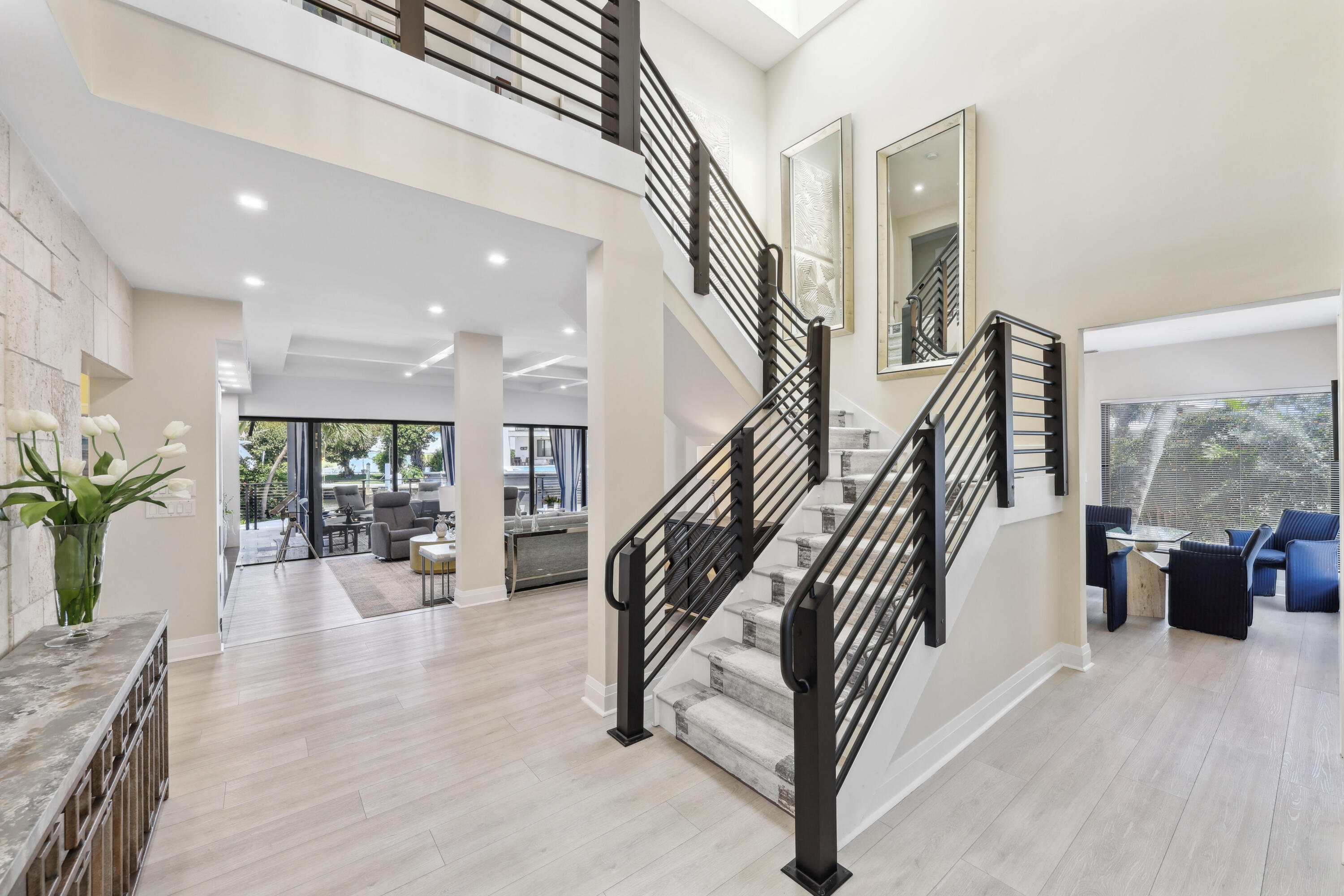 Bright two-story foyer with a dramatic dark-railed staircase and open living areas.