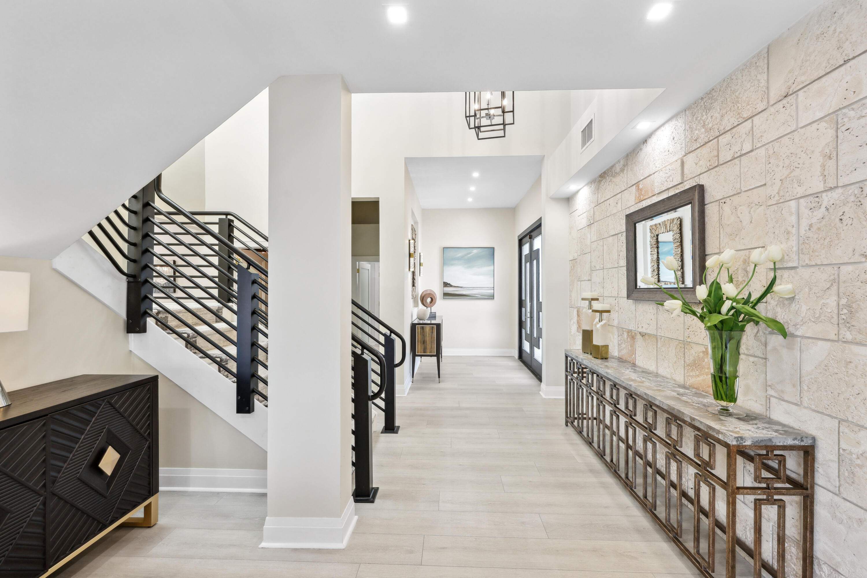 Bright entry hall with a black-railed staircase and stone accent wall.