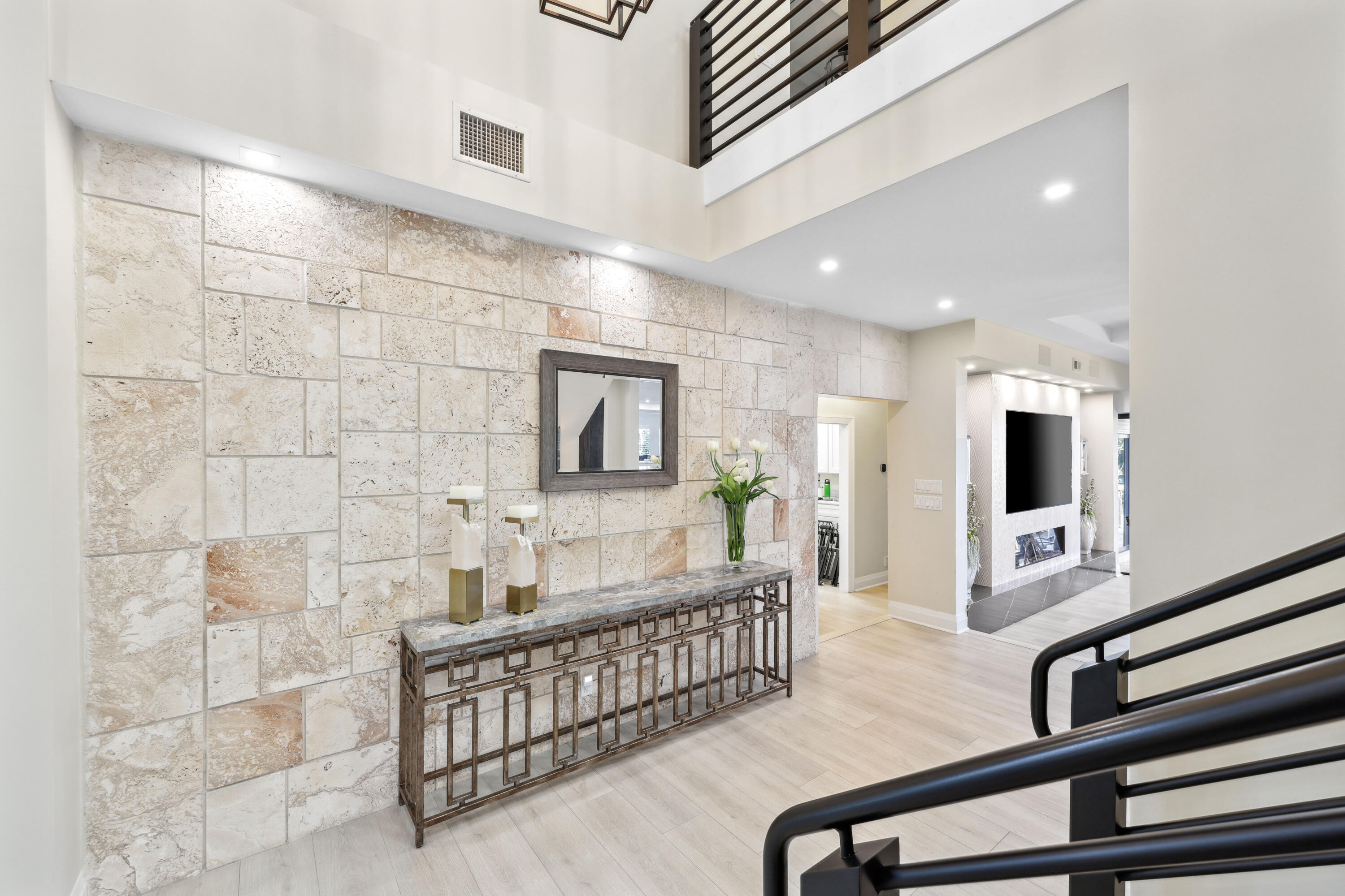 Two-story foyer with a stone accent wall, console table, and black metal staircase railing.