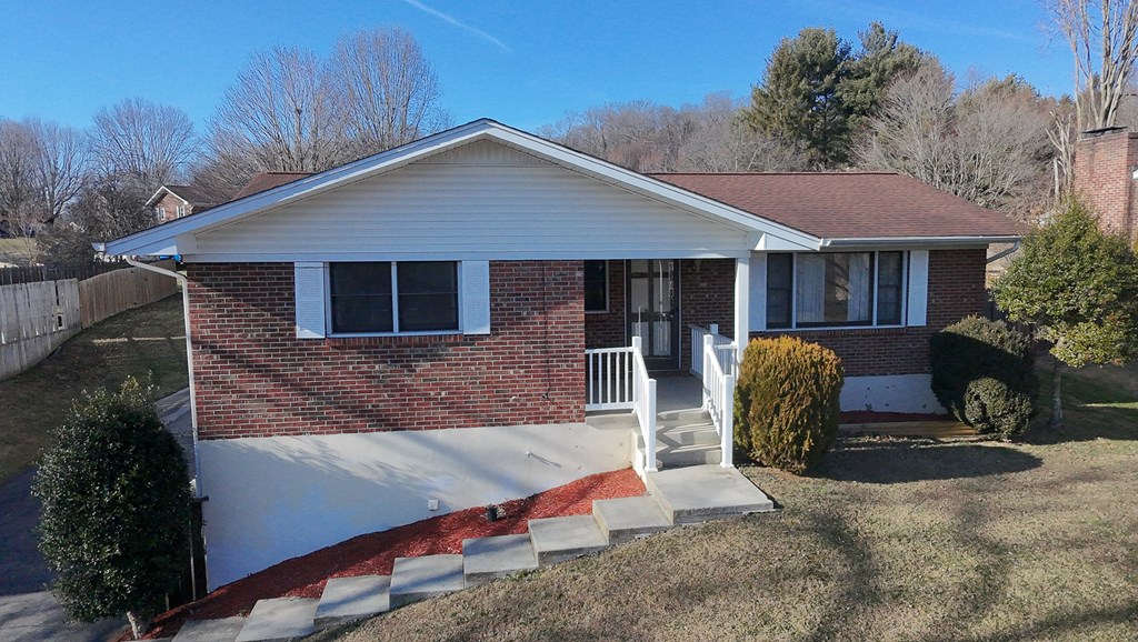 Single-story brick ranch with a broad white gabled roof and covered front porch.