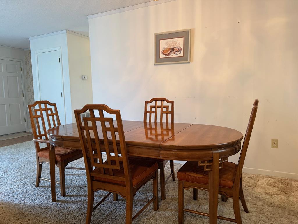 Dining room with an oval wooden table and matching chairs on beige carpet.