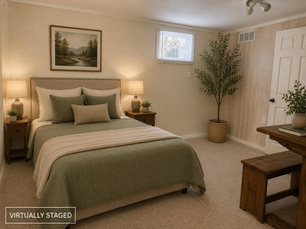 Bedroom with a sage-green bed, matching nightstands, framed landscape art, and a potted tree.