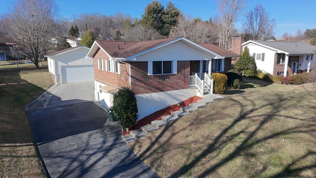 Red-brick home with attached garage, broad driveway, and front steps, seen from above.