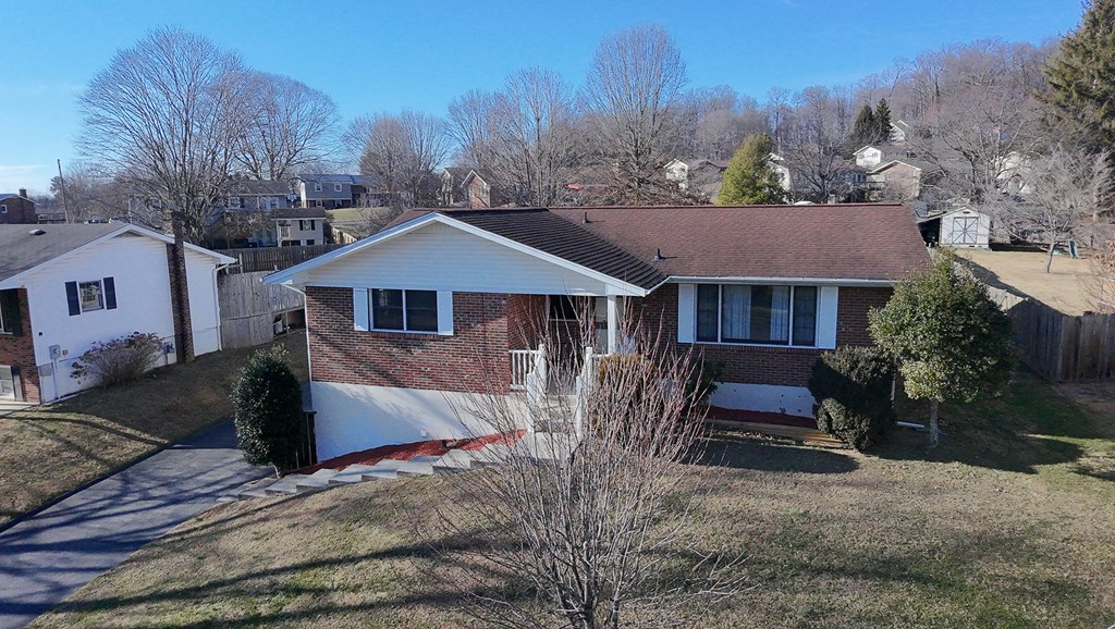 Brick ranch house with a red-brown roof, front steps, and driveway, viewed from above.