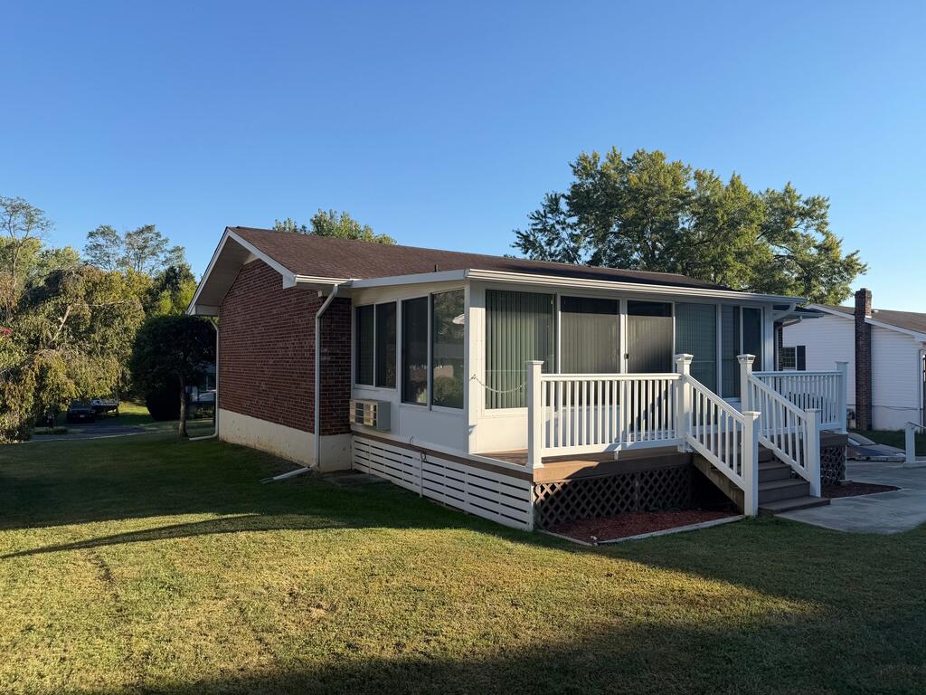 Single-story brick house with an enclosed sunroom and raised white-railed deck.