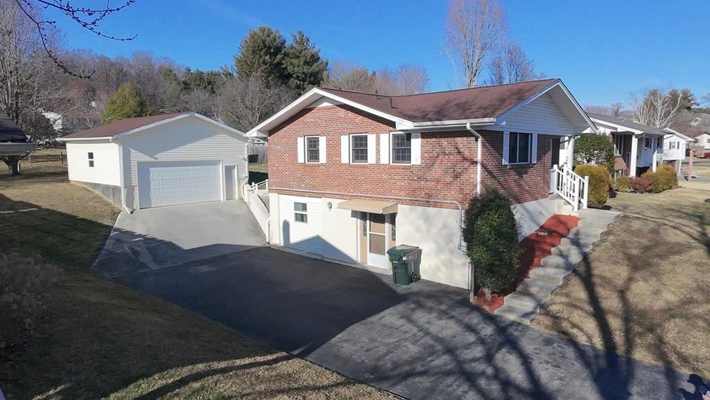 Split-level brick home with a detached garage and broad paved driveway, viewed from above.