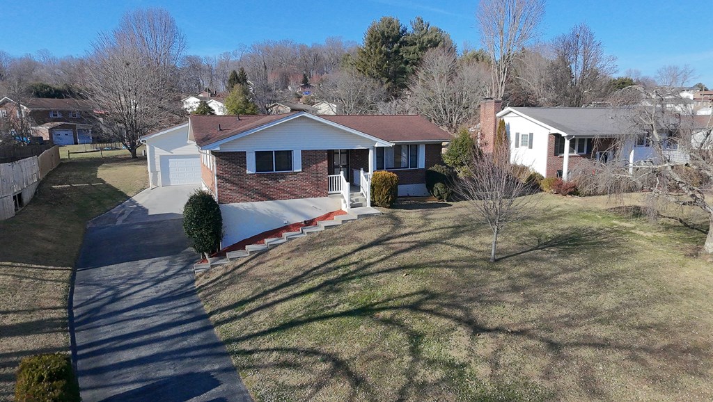 Brick ranch house with an attached garage, long driveway, and broad front lawn.