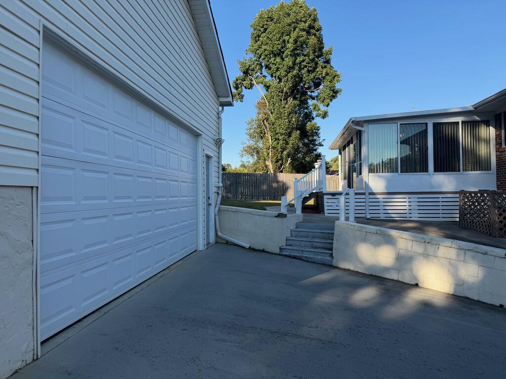 Home exterior with a large white garage, concrete driveway, and raised enclosed sunroom.