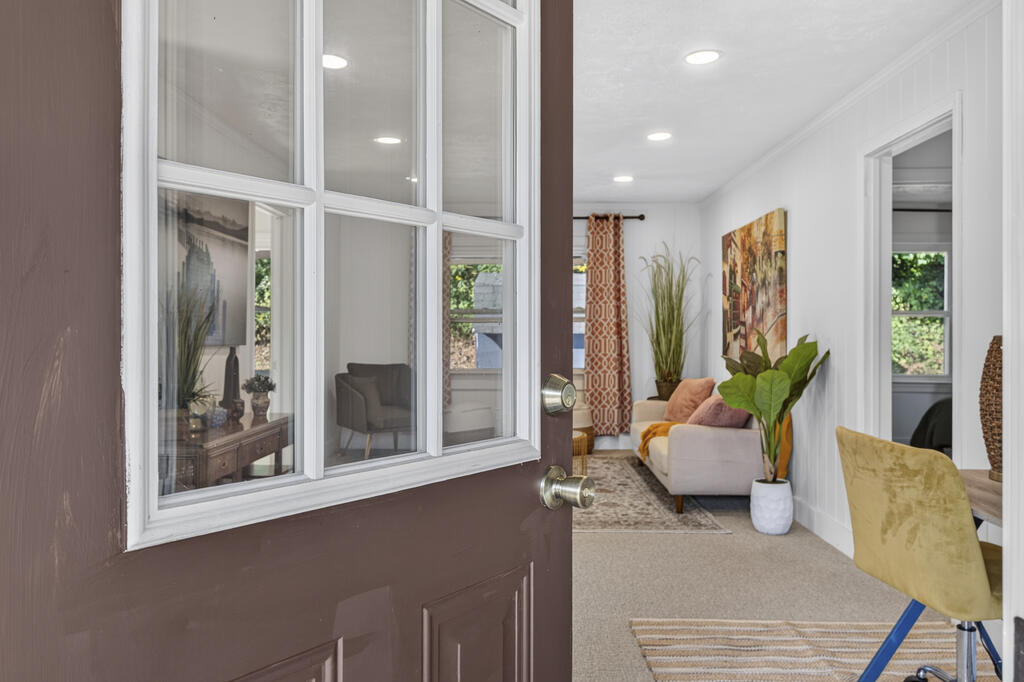 Open front door looking into a staged living room with white walls and colorful furnishings.