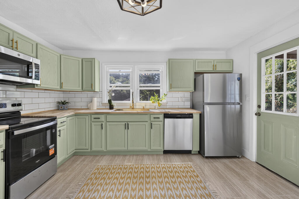 Kitchen with sage green cabinets, stainless appliances, and a windowed door.