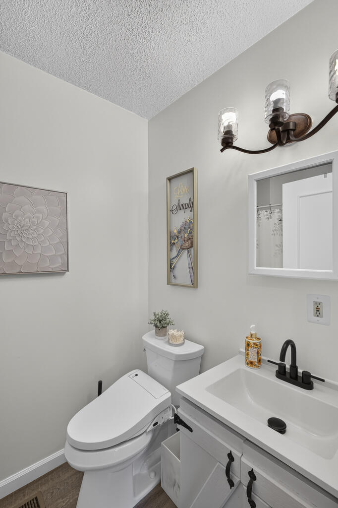 Bathroom with a white vanity, black faucet, framed mirror, and modern toilet.