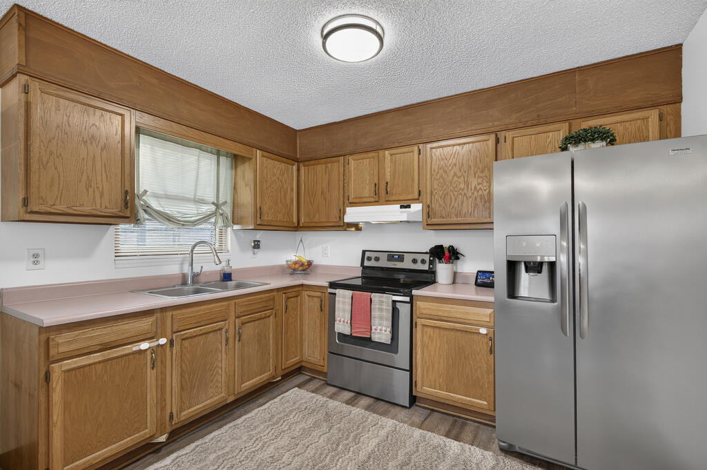 Kitchen with oak cabinets, pink countertops, and stainless steel appliances.