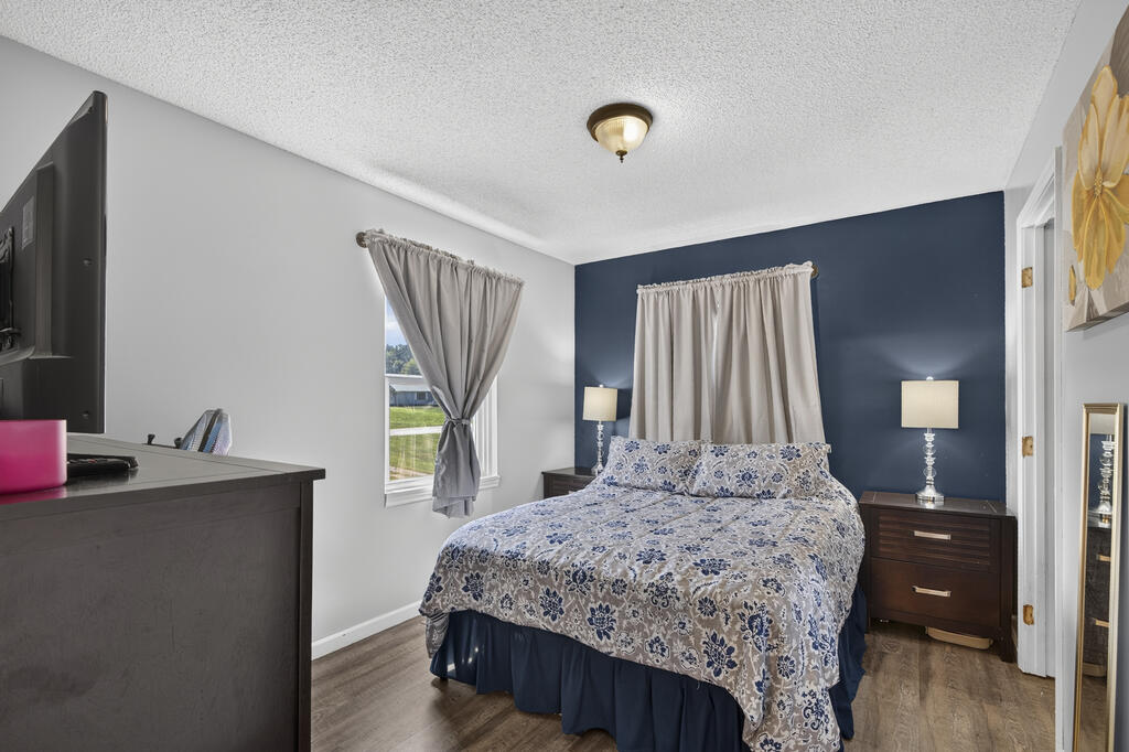 Bedroom with blue-and-white floral bedding, a navy accent wall, and dark bedside tables.