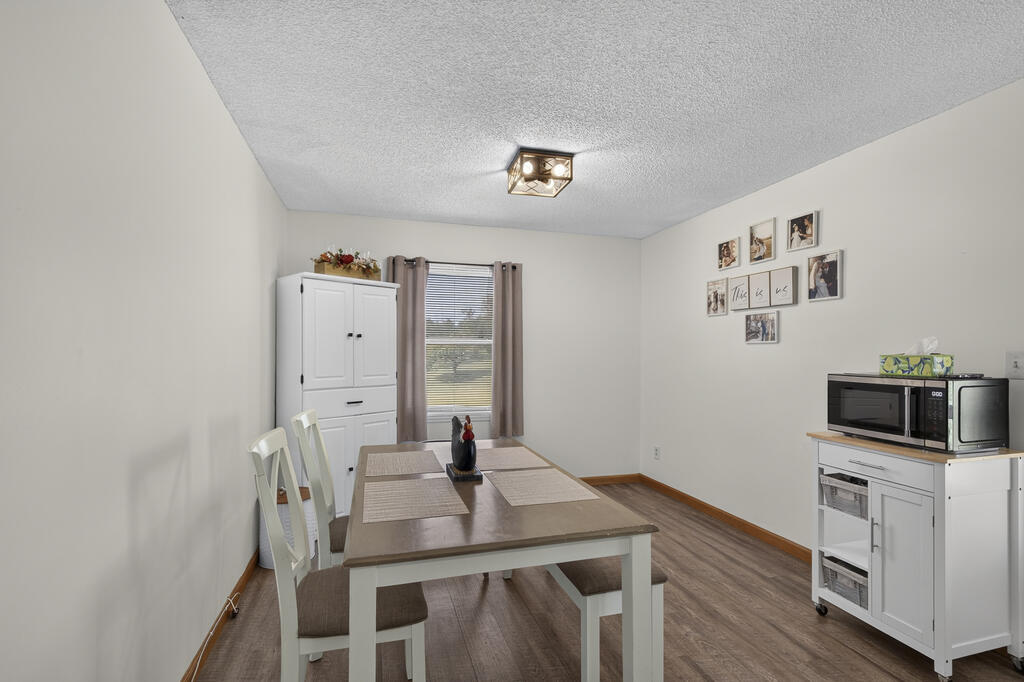 Dining room with a table, white storage cabinet, window, and microwave cart.