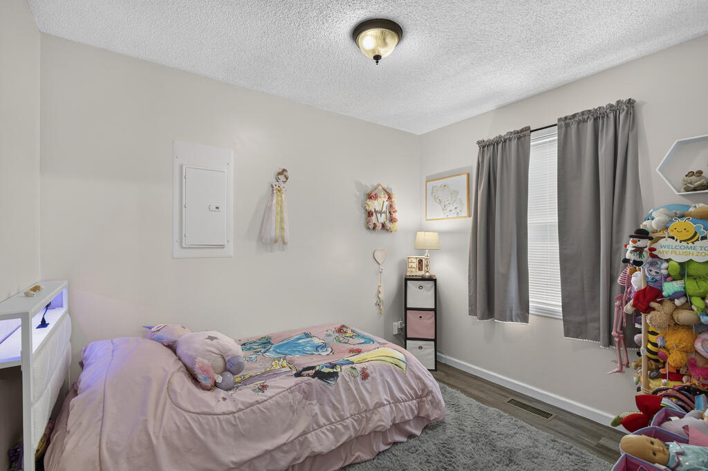 Child's bedroom with colorful cartoon bedding and a shelf crowded with plush toys.