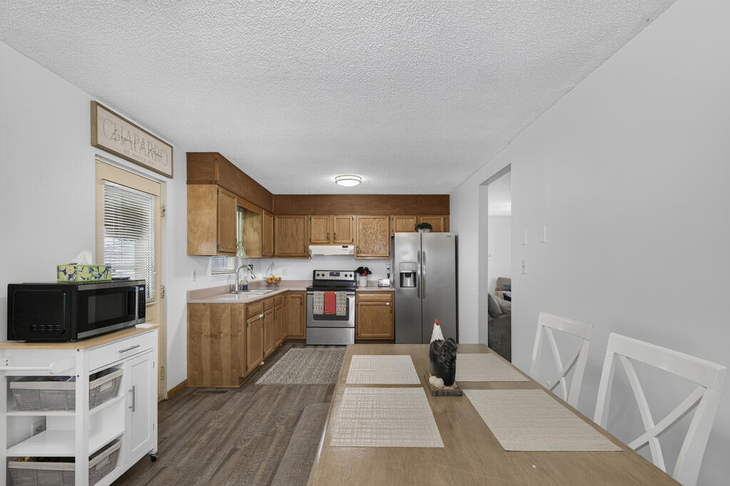 Kitchen and dining area with oak cabinets, stainless steel appliances, and a table set with white chairs.