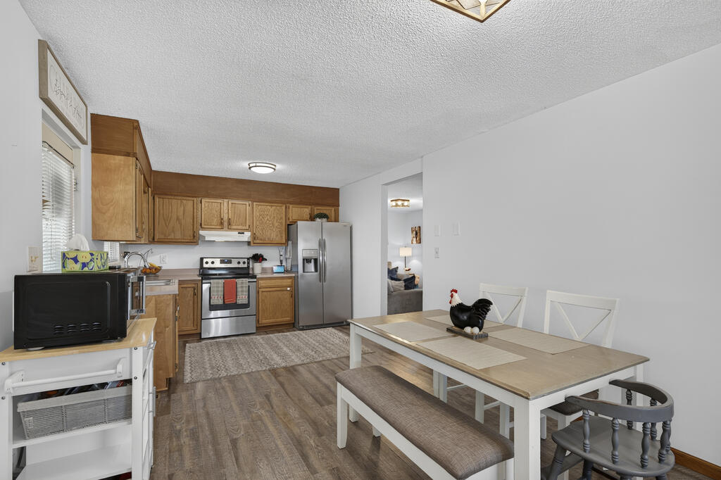 Kitchen and dining area with wood cabinets, stainless steel appliances, and a white table with benches.