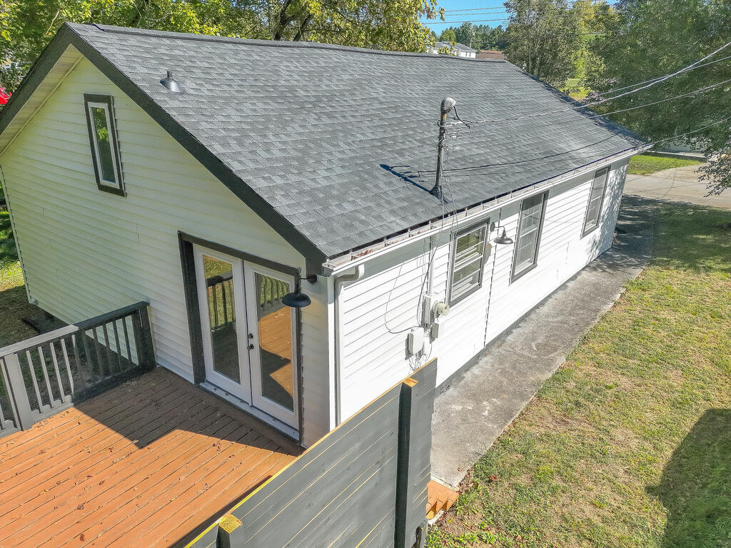 White-sided house with a broad gray roof and wooden deck, seen from above.