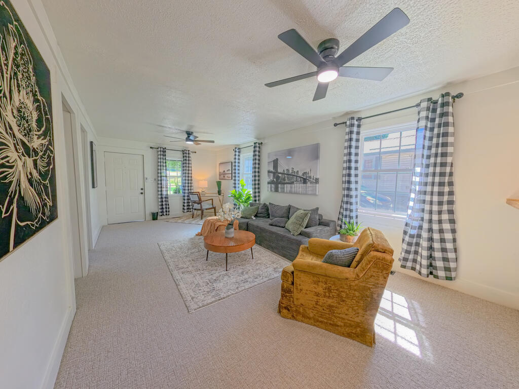 Furnished living room with a gray sofa, mustard armchair, patterned rug, and checked curtains.