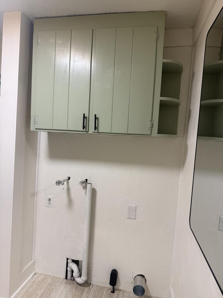 Bathroom with wall cabinet, mirror, and exposed plumbing where a fixture is missing.