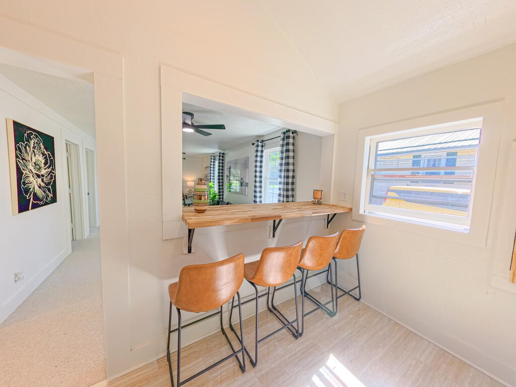 Breakfast bar with a wood countertop and four brown stools beside a large window.