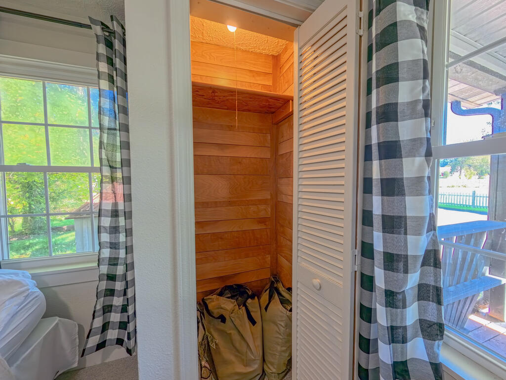 Cedar-lined storage closet with a louvered door and bags on the floor.