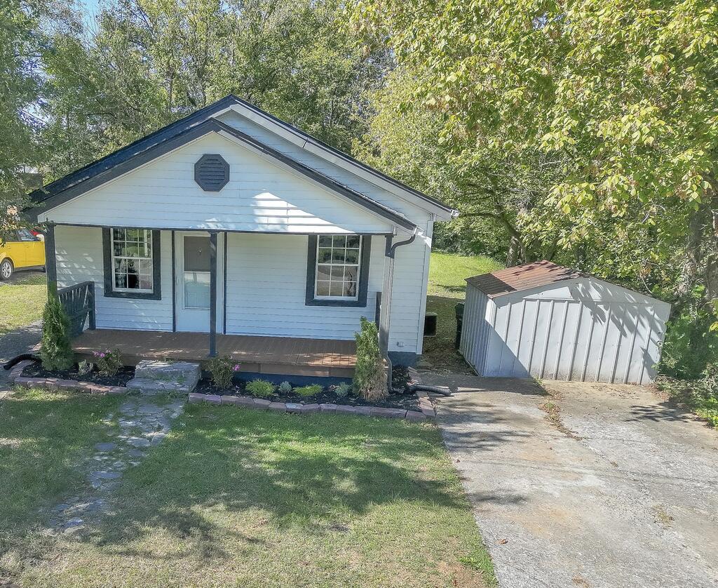 White single-story house with a covered porch and detached shed beside the driveway.
