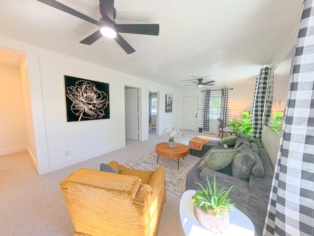 Living room with a gray sofa, mustard-yellow armchair, ceiling fans, and plaid curtains.