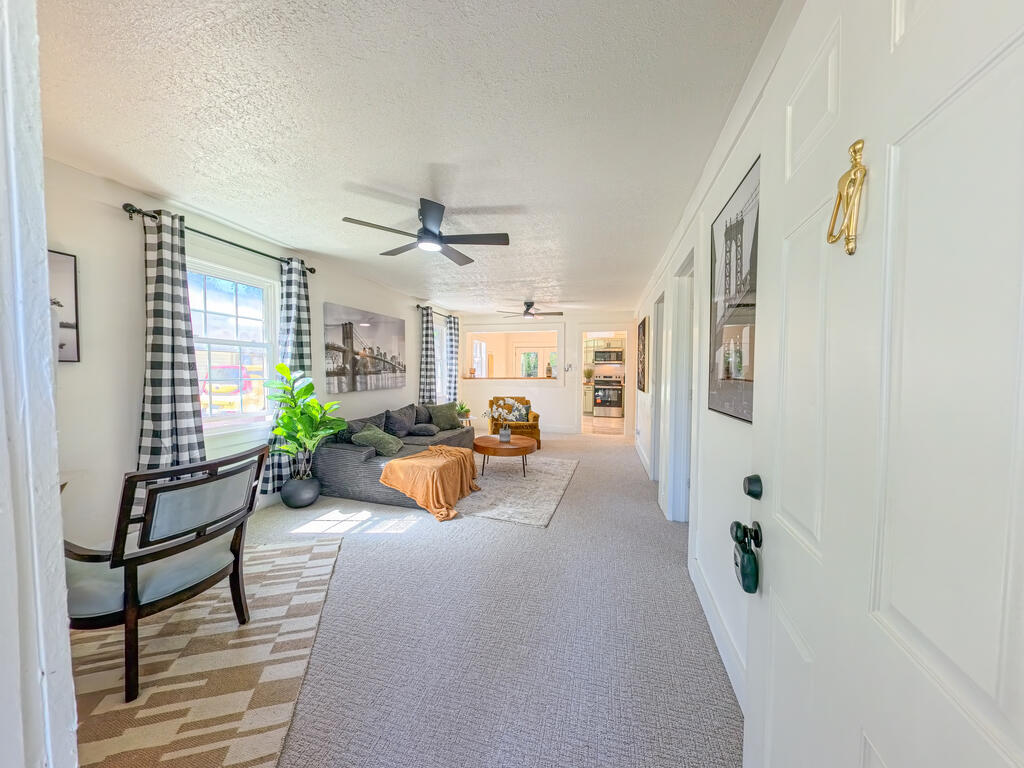 Living room with a gray sofa, patterned curtains, and a view toward the kitchen.