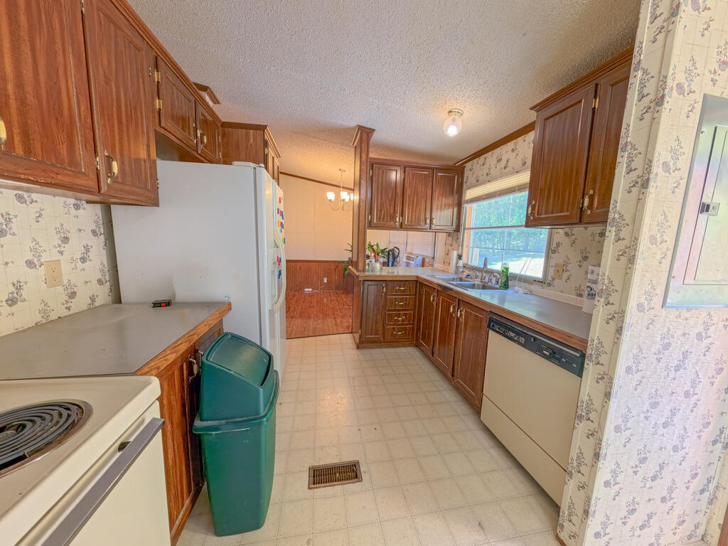 Kitchen with dark wood cabinets, floral wallpaper, and a sink beneath a large window.