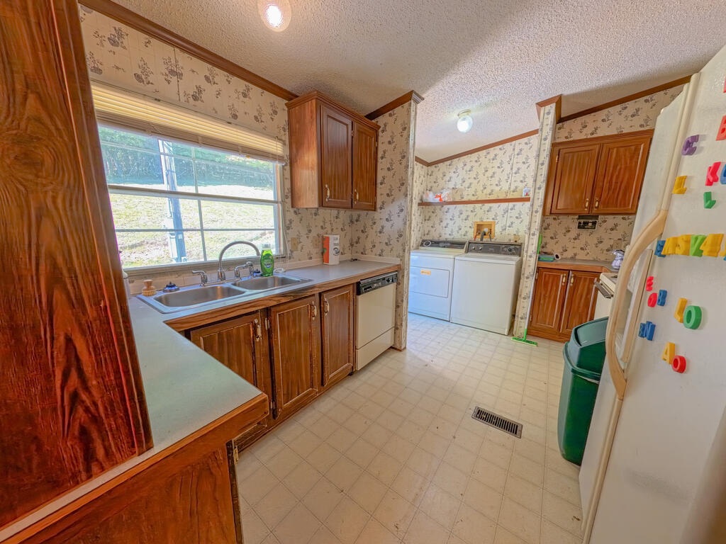 Kitchen with wood cabinets and a sink beneath a window; washer and dryer at the back.