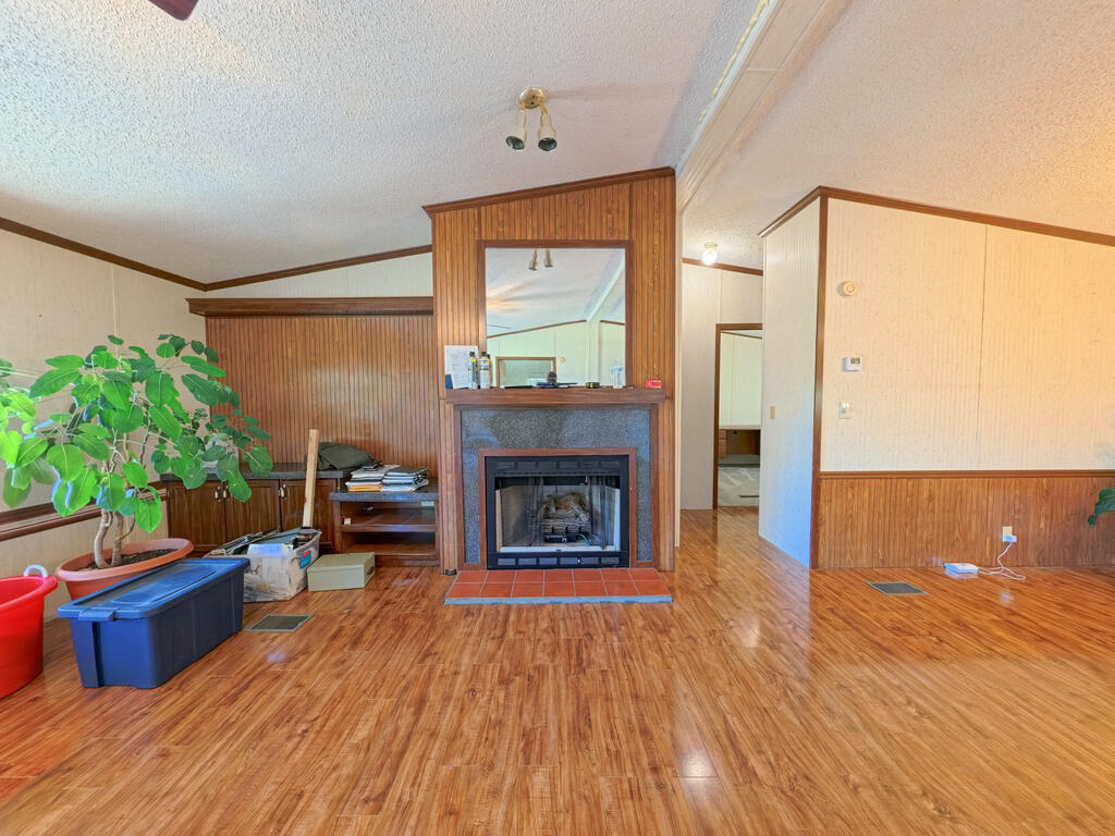 Living room with a wood-paneled fireplace, large mirror, and wood-look flooring.