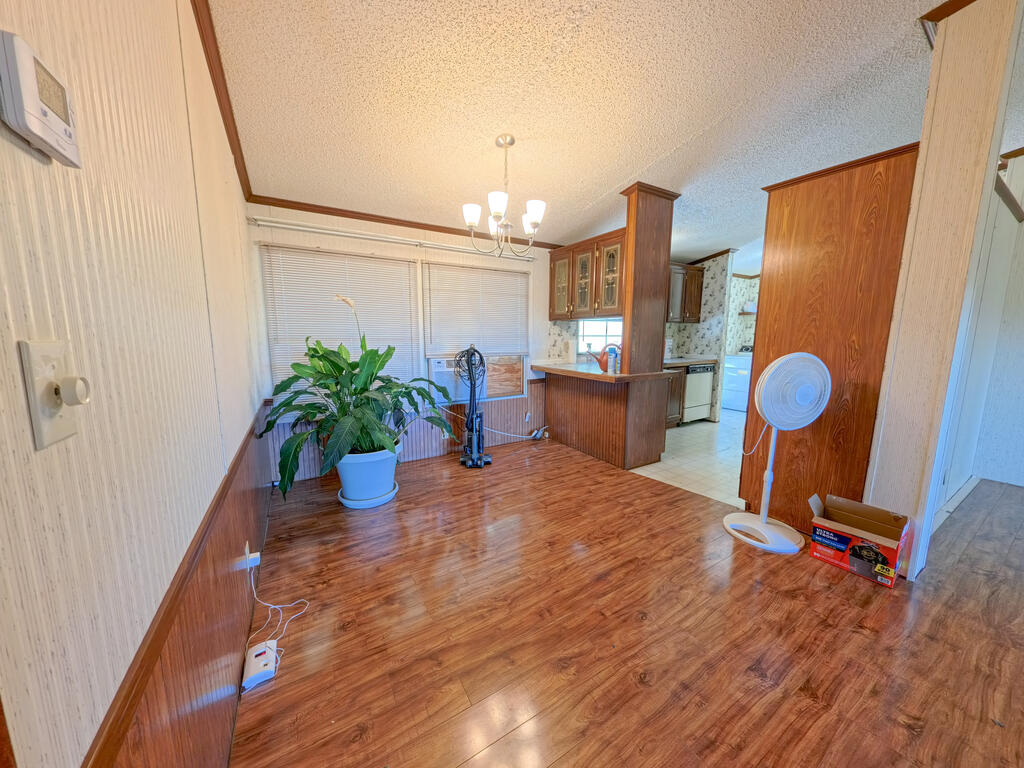Dining area with wood-look flooring, a breakfast bar, and a potted plant beside the kitchen.