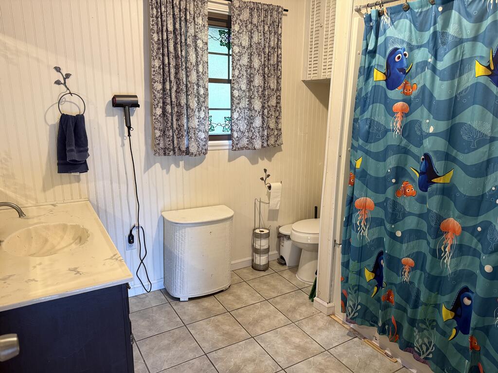 Bathroom with a dark blue vanity, tiled floor, and blue Finding Nemo shower curtain.