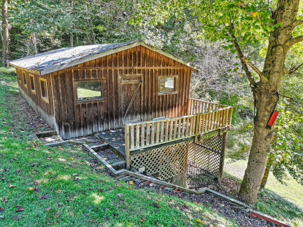 Wooden outbuilding with a raised deck and lattice skirting among trees.