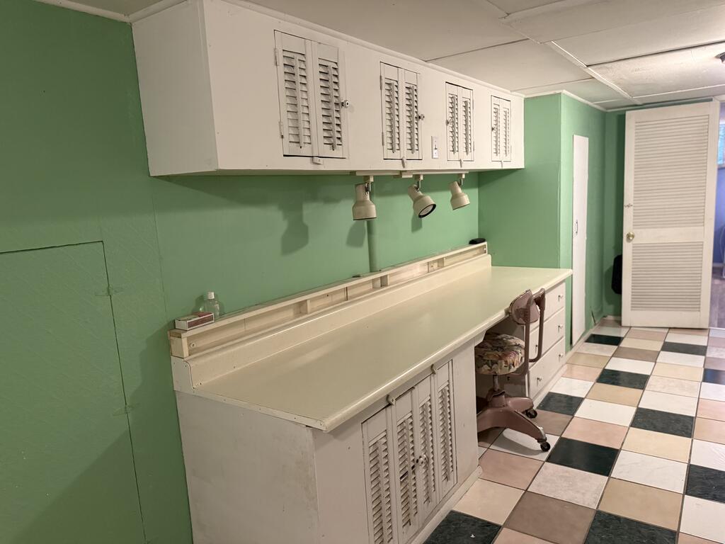 Vanity area with a long cream counter, louvered cabinets, and checkerboard tile floor.