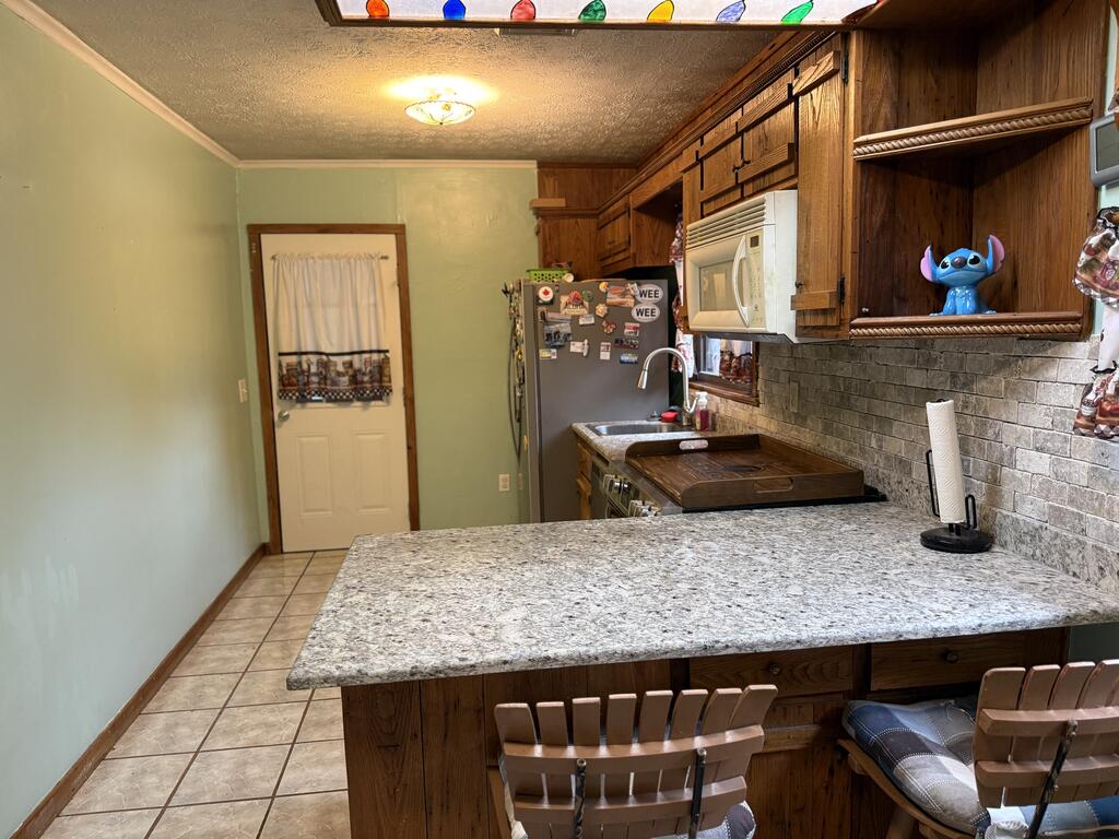 Kitchen with a large stone island, wood cabinetry, and stools.