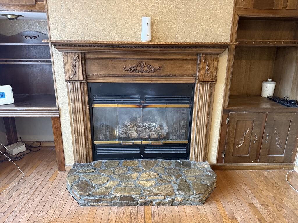 Ornate wooden fireplace with a black gas insert and broad stone hearth.