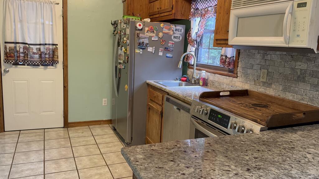Kitchen with granite counters, wood cabinets, tile backsplash, and stainless steel appliances.